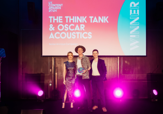 Two Members of The Think Tank Team accepting an award on stage at the UK Content awards 2024 for Oscar Acoustics with the host