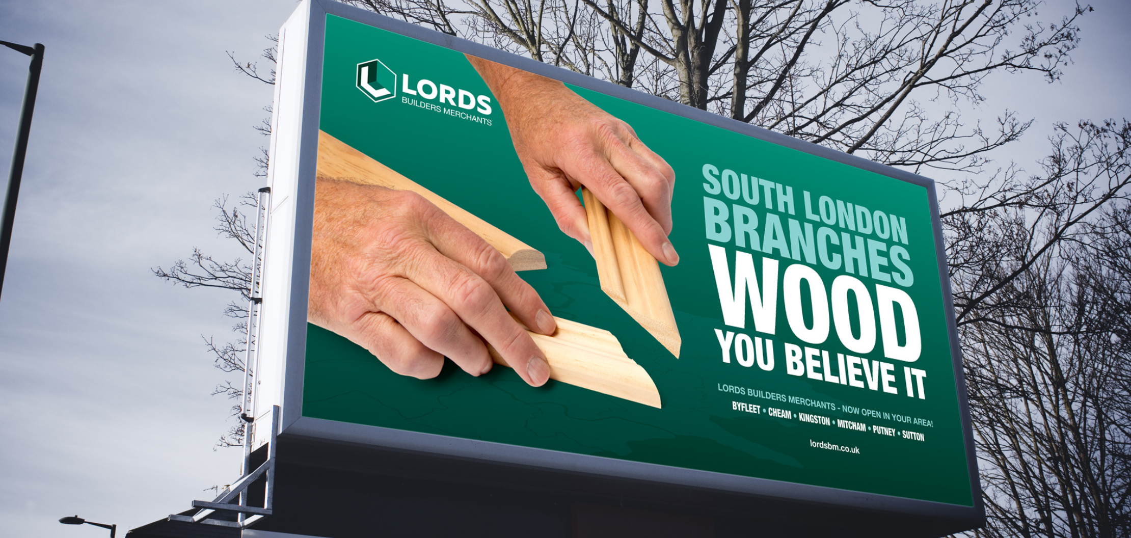 A billboard with branded logo, slogan 'wood you believe it' and building imagery