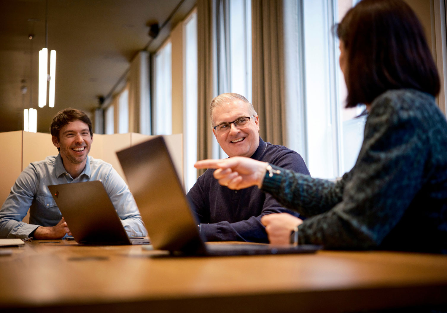 Members of the Think Tank Team having a discussion around a table with laptops.